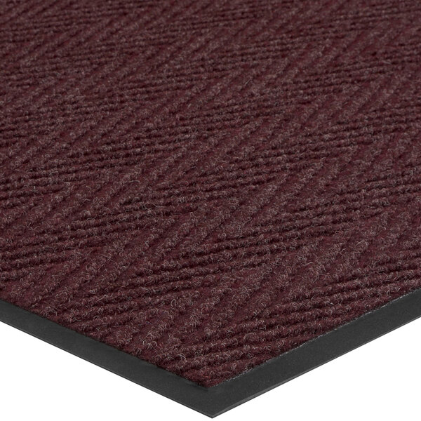 A Lavex burgundy carpet mat with a black border and chevron pattern.