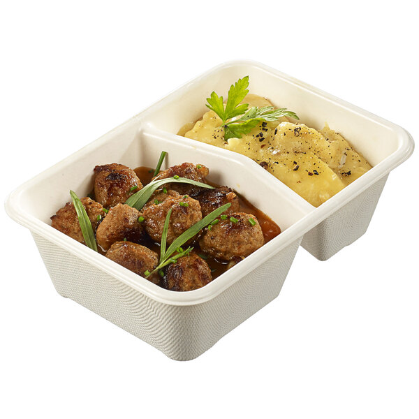 A Solia laminated sugarcane container with 2 compartments holding meatballs and mashed potatoes.