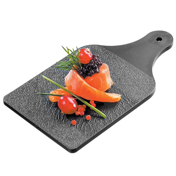 A Solia black slatelike mini display board with salmon and vegetables on it.