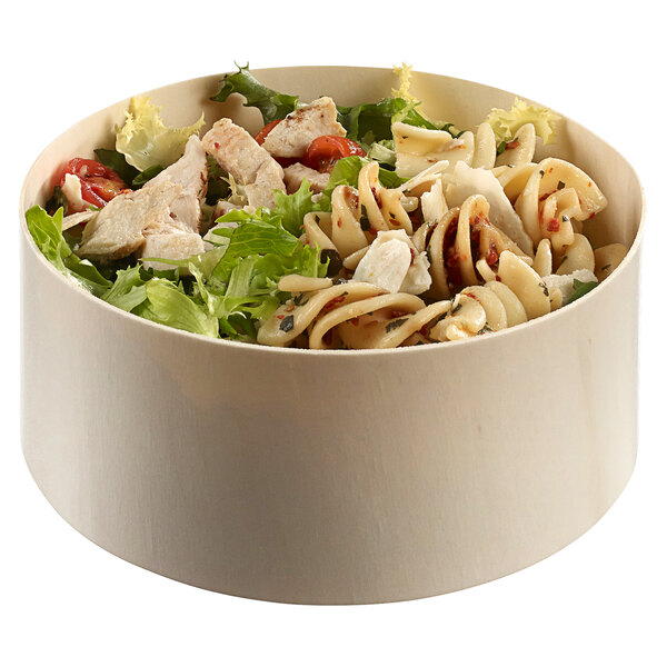 A Solia wooden bowl filled with pasta, chicken, and vegetables.