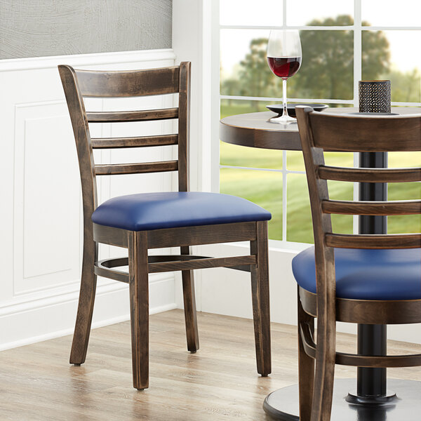 Two Lancaster Table & Seating wood chairs with navy vinyl seats at a table in a restaurant