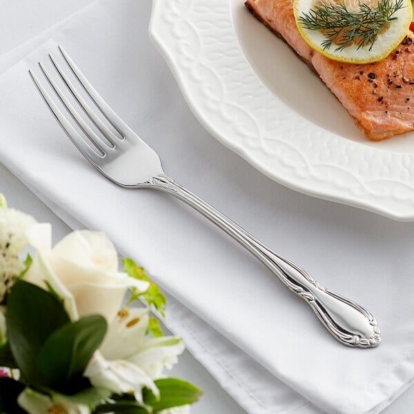 An Acopa stainless steel fork on a plate with a piece of salmon, lemon, and dill.