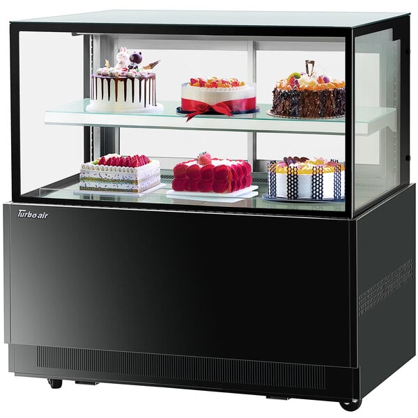 A Turbo-Air black refrigerated bakery display case with cakes on two tiers.