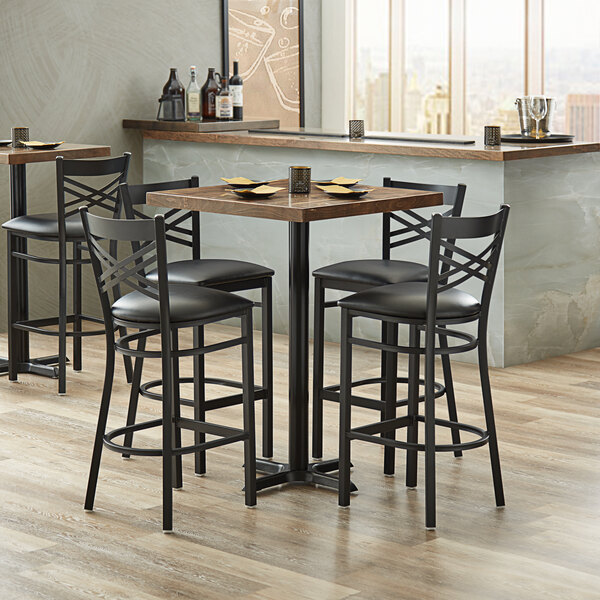 A Lancaster Table & Seating butcher block table with 4 black chairs around it.