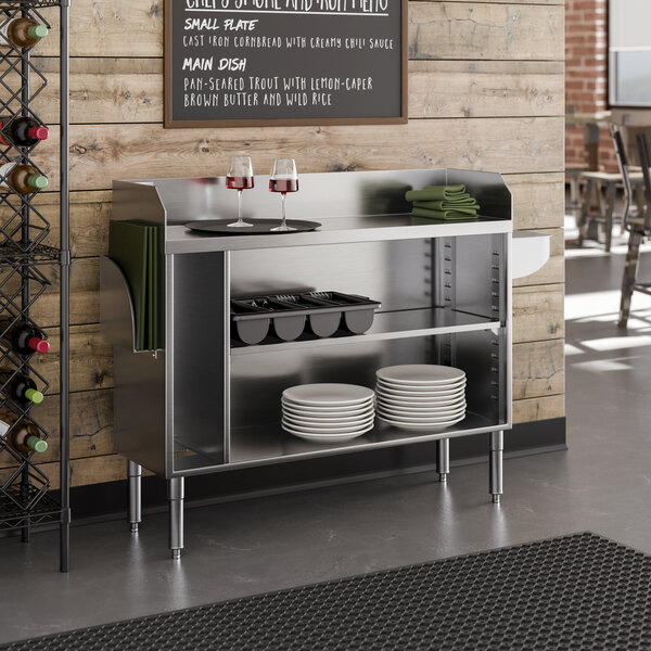 A stainless steel bussing and waitress station with shelves, a pan holder, and space for plates and utensils.