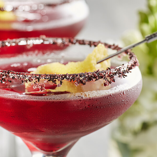 Two martinis garnished with Wild Hibiscus Pyramid Salt Flakes on a table in a cocktail bar.