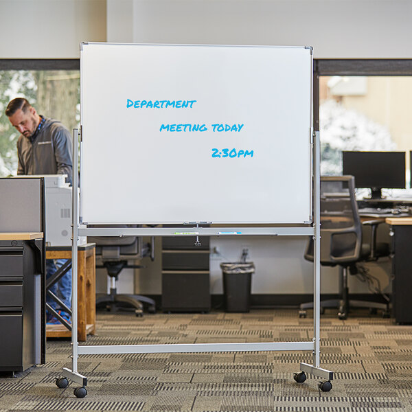 A man using a Dynamic by 360 Office Furniture whiteboard in an office.