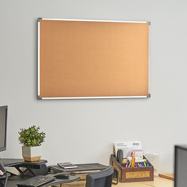 A Dynamic by 360 Office Furniture cork board with aluminum frame mounted on a wall.