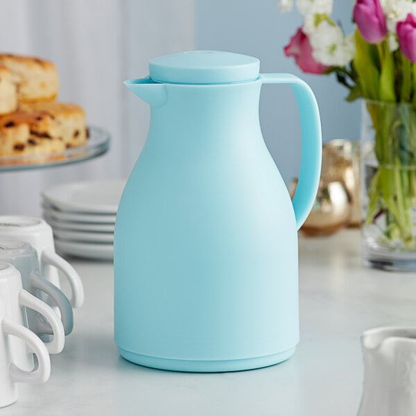 An Acopa blue thermal carafe on a table with a white mug.