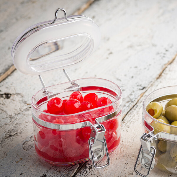 Two Tablecraft oval plastic condiment jars filled with green and red olives.
