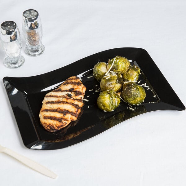 A Fineline black plastic luncheon plate with grilled meat and vegetables on it.