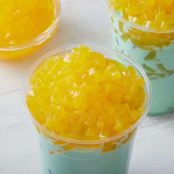 A cup of ice cream with yellow jelly on top.