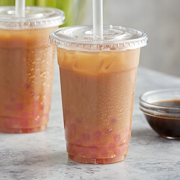 Two plastic cups of brown ginger bubble tea with a straw.