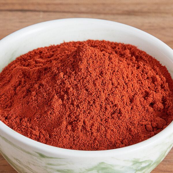 A bowl of Regal Ground Annatto powder on a wooden table.
