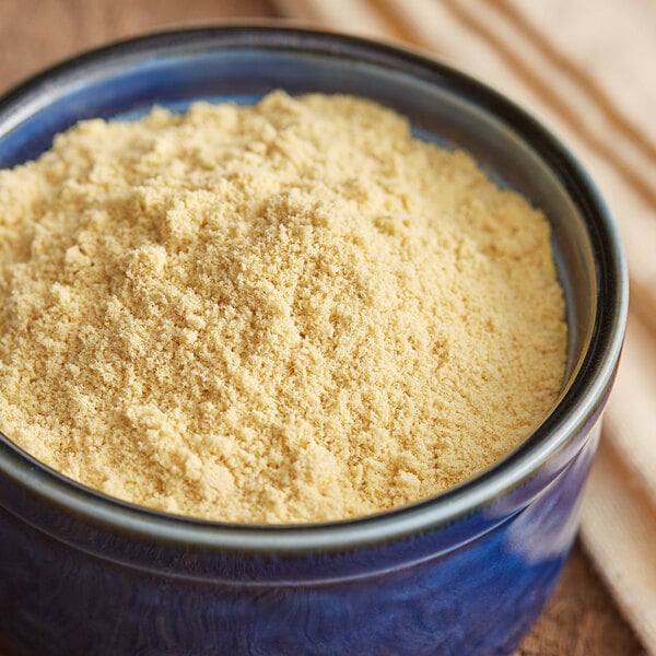 A bowl of Regal Ground Hot English Mustard Seed powder on a wooden table.