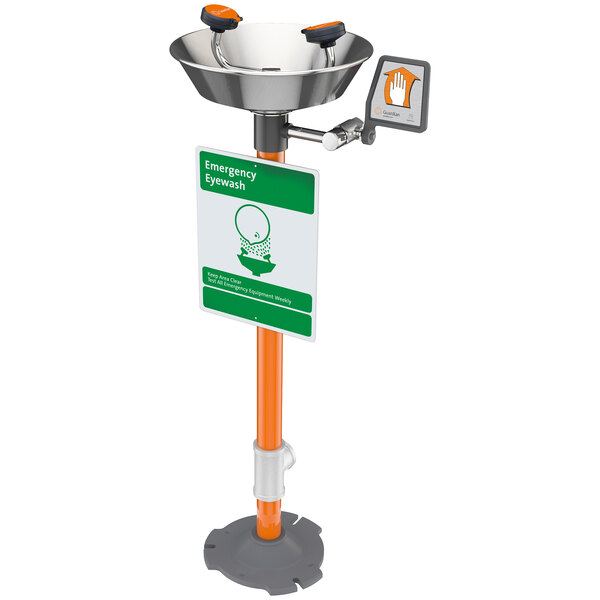 A Guardian Equipment eye wash station pedestal with a green and orange sign and a black and orange bowl.