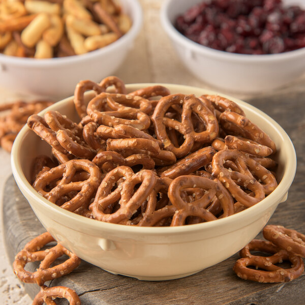 A Carlisle tan melamine nappie bowl filled with pretzels.