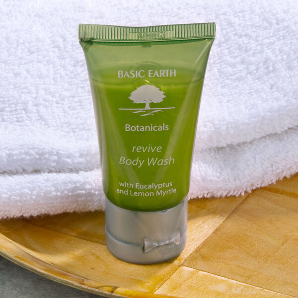 A white plate with a towel and a green tube of Basic Earth Botanicals Reviving Body Wash.