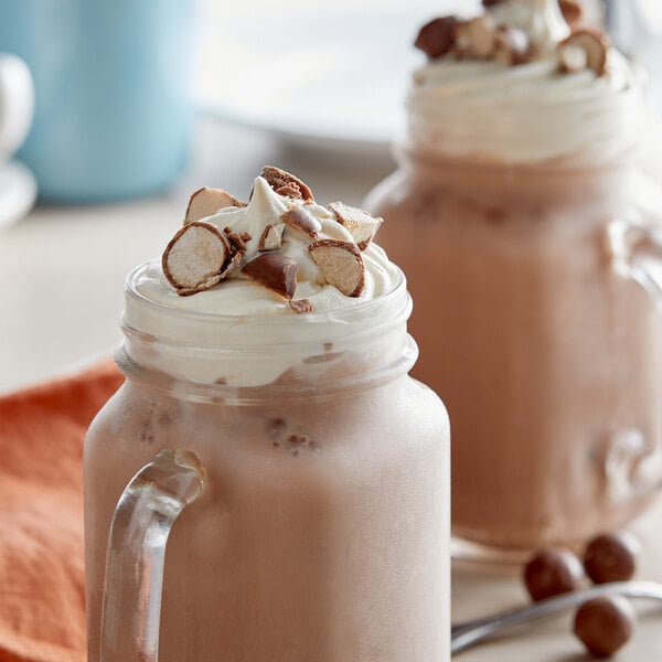 A glass jar of J. Hungerford Smith Liquid Malt Syrup in a chocolate milkshake with whipped cream on top.