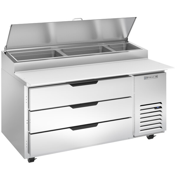 A Beverage-Air stainless steel refrigerated pizza prep table with three drawers and clear lids.