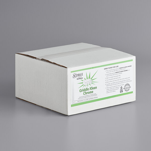 A white box with green and white text that reads "Noble Chemical QuikPacks Chrome Griddle Kleen" on a counter.