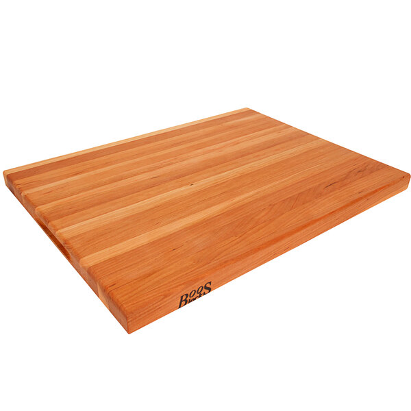 A John Boos cherry wood cutting board with hand grips and black logo.