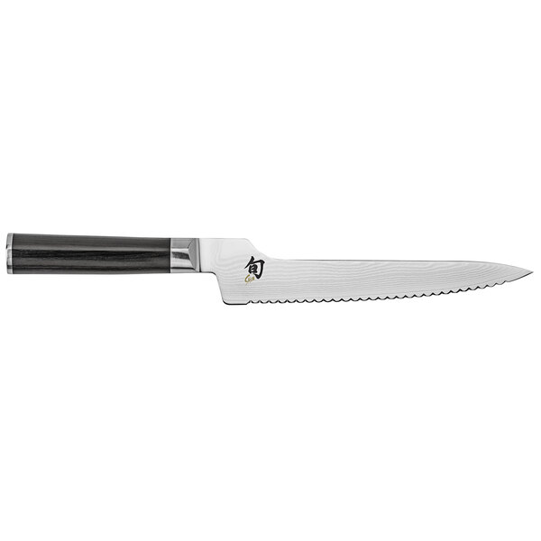 A Shun Classic bread knife with a black handle and silver blade on a counter.