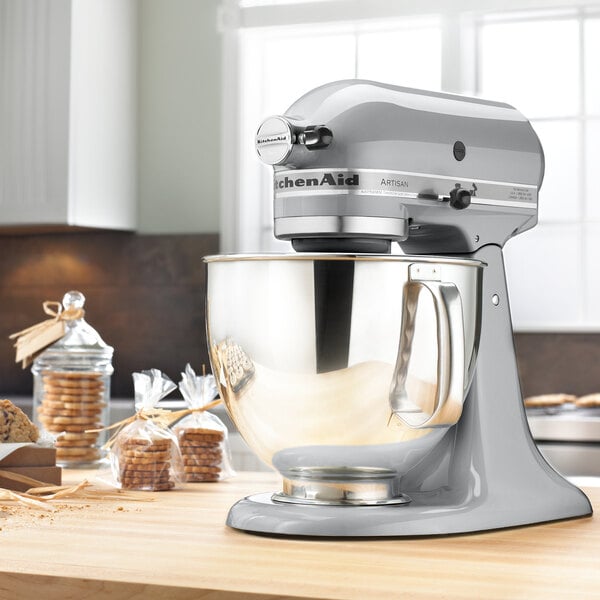 A KitchenAid metallic chrome mixer on a countertop with cookies in the bowl.
