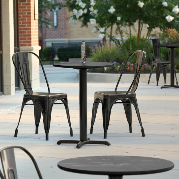 A black Lancaster Table & Seating Excalibur table top on a table outside.