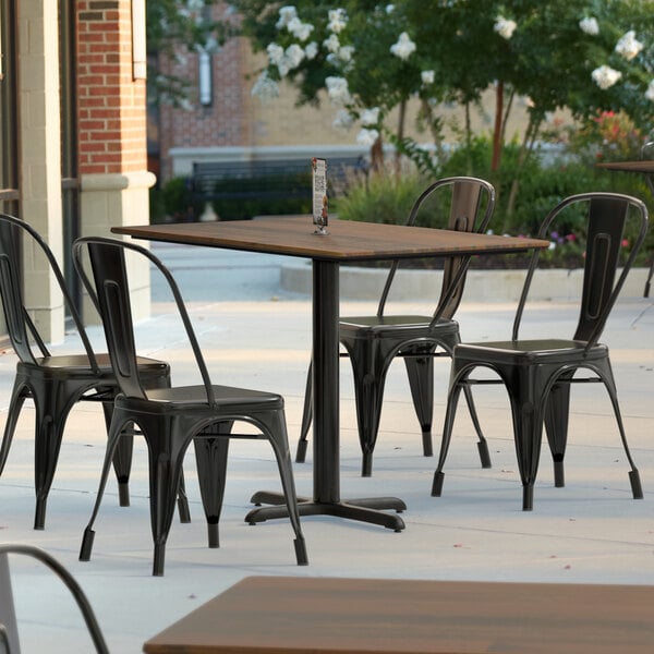 A Lancaster Table & Seating rectangular table top with a textured farmhouse finish on a patio with chairs.