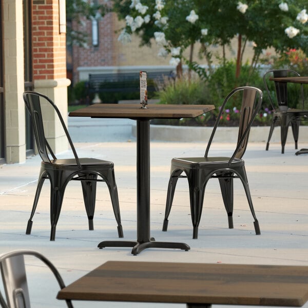 A Lancaster Table & Seating Excalibur wood table top with a textured finish on a table with chairs on a patio.