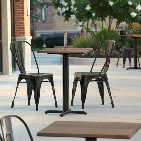 A Lancaster Table & Seating square table and black chairs on a patio.