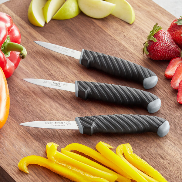 A Schraf 3-piece paring knife set with TPRgrip handles next to fruit.