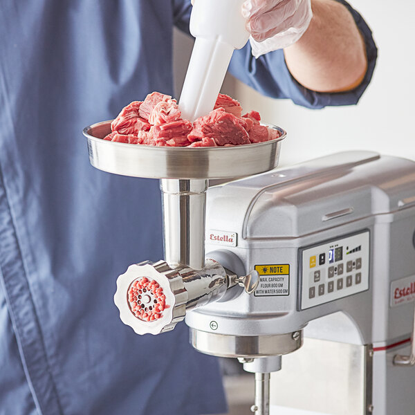 A man using an Estella mixer hub meat grinder attachment to grind meat.