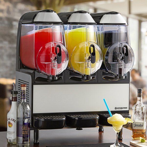 A Stoelting triple frozen beverage machine with different colored drinks inside.