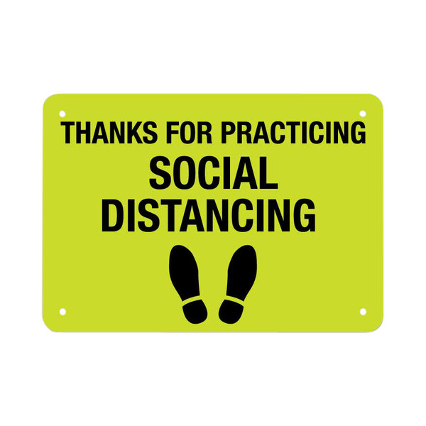 A yellow sign with black text and footprints reading "Thanks For Practicing Social Distancing" with a black footprint symbol.