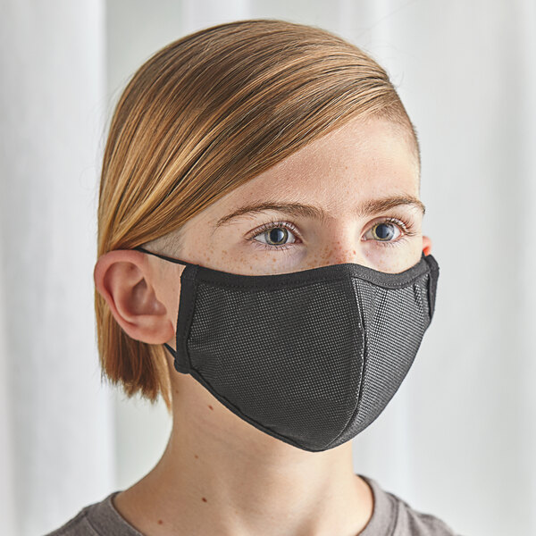 A young girl wearing a black Mercer Culinary youth face mask.