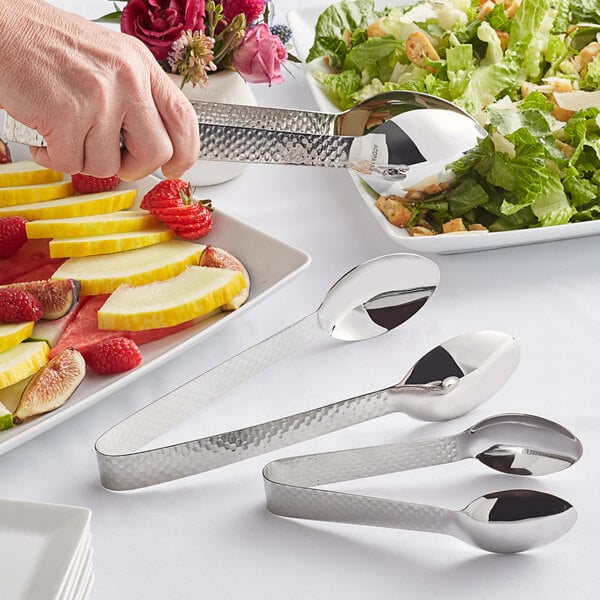 Acopa stainless steel serving tongs being used to serve melon slices.