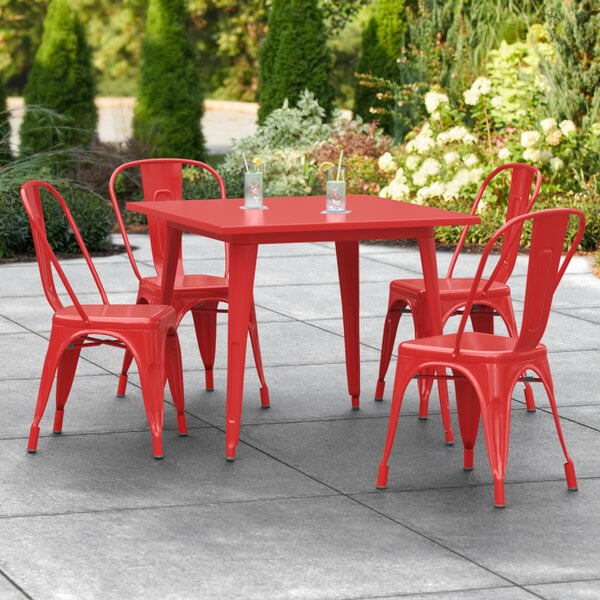 A Lancaster Table & Seating red outdoor table with chairs on a patio.