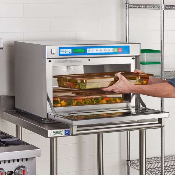 A man using a Solwave commercial steamer to heat food in a tray.