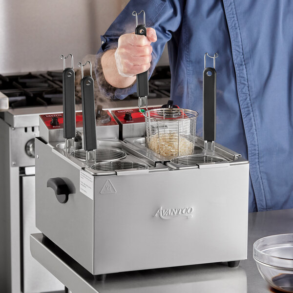 A man using an Avantco countertop pasta cooker to make food.