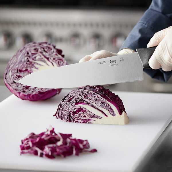 A person using a Choice 10" chef knife to cut cabbage on a cutting board.