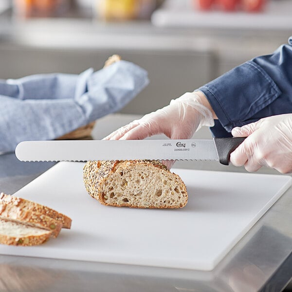 A person using a Choice serrated bread knife to slice bread on a cutting board.