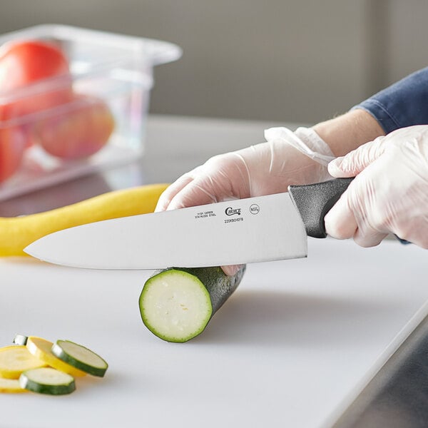 A person in gloves cutting vegetables on a cutting board with a Choice 8" Chef Knife.
