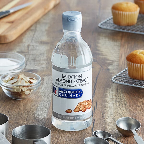 A close up of a McCormick Culinary Imitation Almond Extract bottle next to cupcakes.