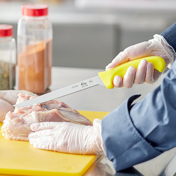 A person using a Choice neon yellow fillet knife to cut meat.