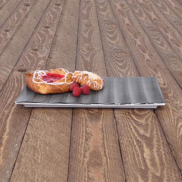A black textured melamine platter with pastries and raspberries on it.