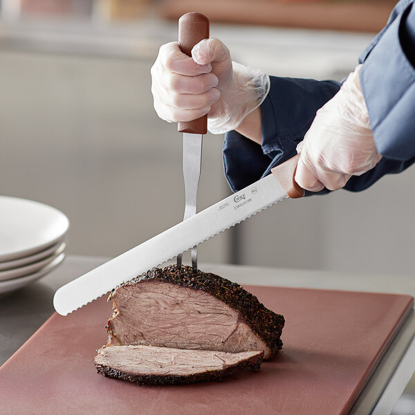 A person slicing meat with a Choice serrated bread knife with a brown handle.