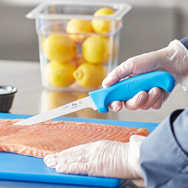 A person using a Choice narrow stiff boning knife with a blue handle to cut fish.