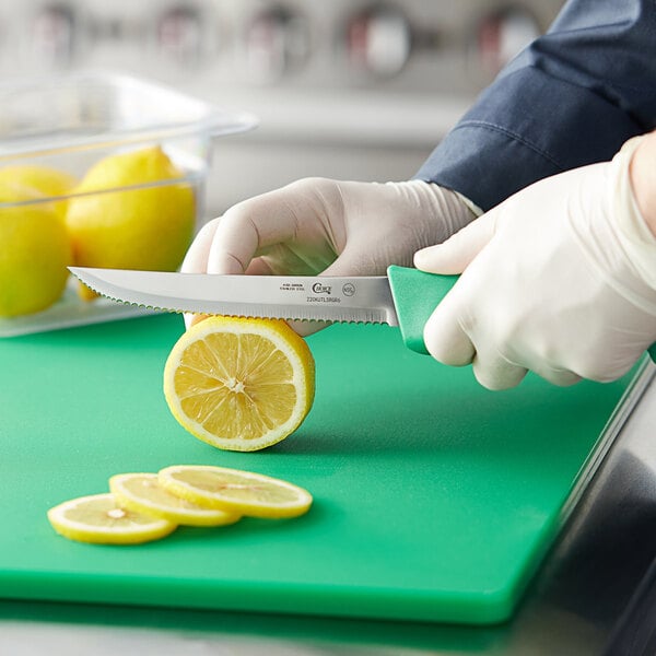 A person using a Choice serrated utility knife to cut a lemon.